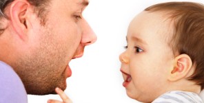Ein Baby ahmt die Mundbewegungen seines Vaters nach