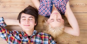 Zwei Jugendliche liegen Kopf an Kopf auf einem Holzsteg