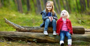 Zwei kleine Mädchen sitzen auf einem Baumstamm