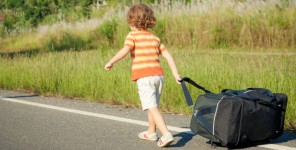 Kleines Kind mit großer Reisetasche auf der Straße