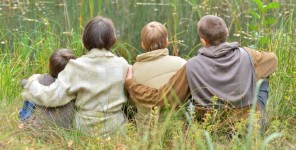 Rückansicht einer vierköpfigen Familie in der Wiese