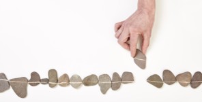 Eine Hand fügt eine Reihe von Steinen zu einer Linie