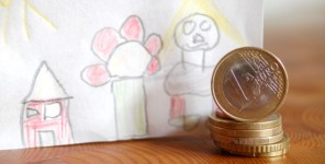 Ein-Euro-Münzen vor einer Kinderzeichnung